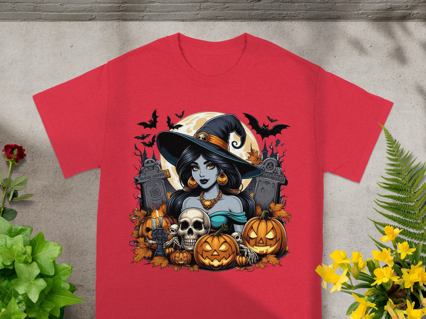 Halloween witch illustration with pumpkins, skulls, bats, and tombstones on a red shirt.