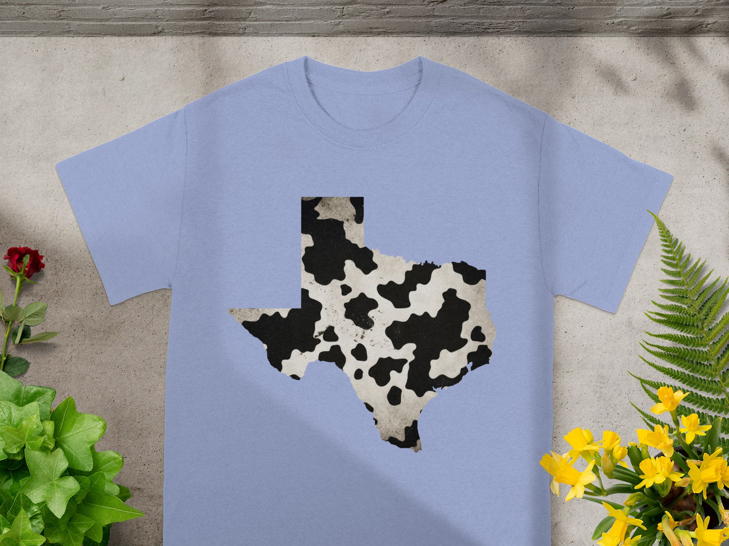 Light blue t-shirt with a black and white cow print Texas outline.