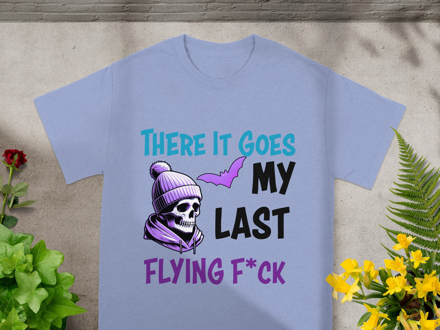 Light purple t-shirt with skull wearing a beanie and bat art, text reads "THERE IT GOES MY LAST FLYING F*CK".