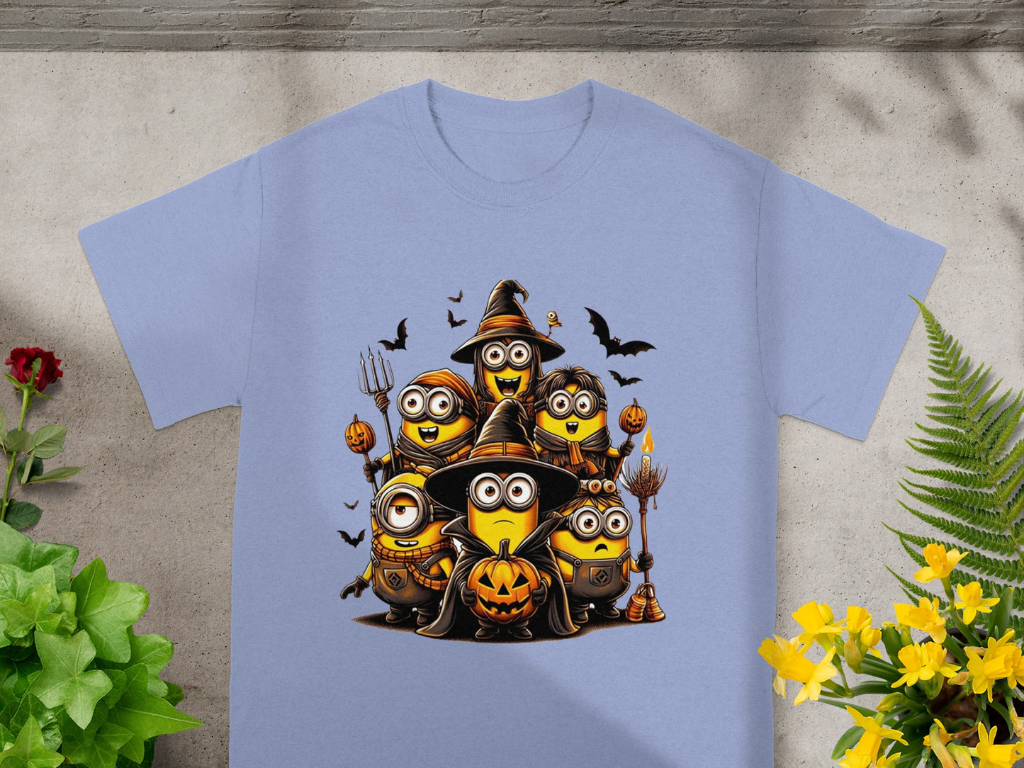 Minions in Halloween costumes with pumpkins and bats on a light blue t-shirt.