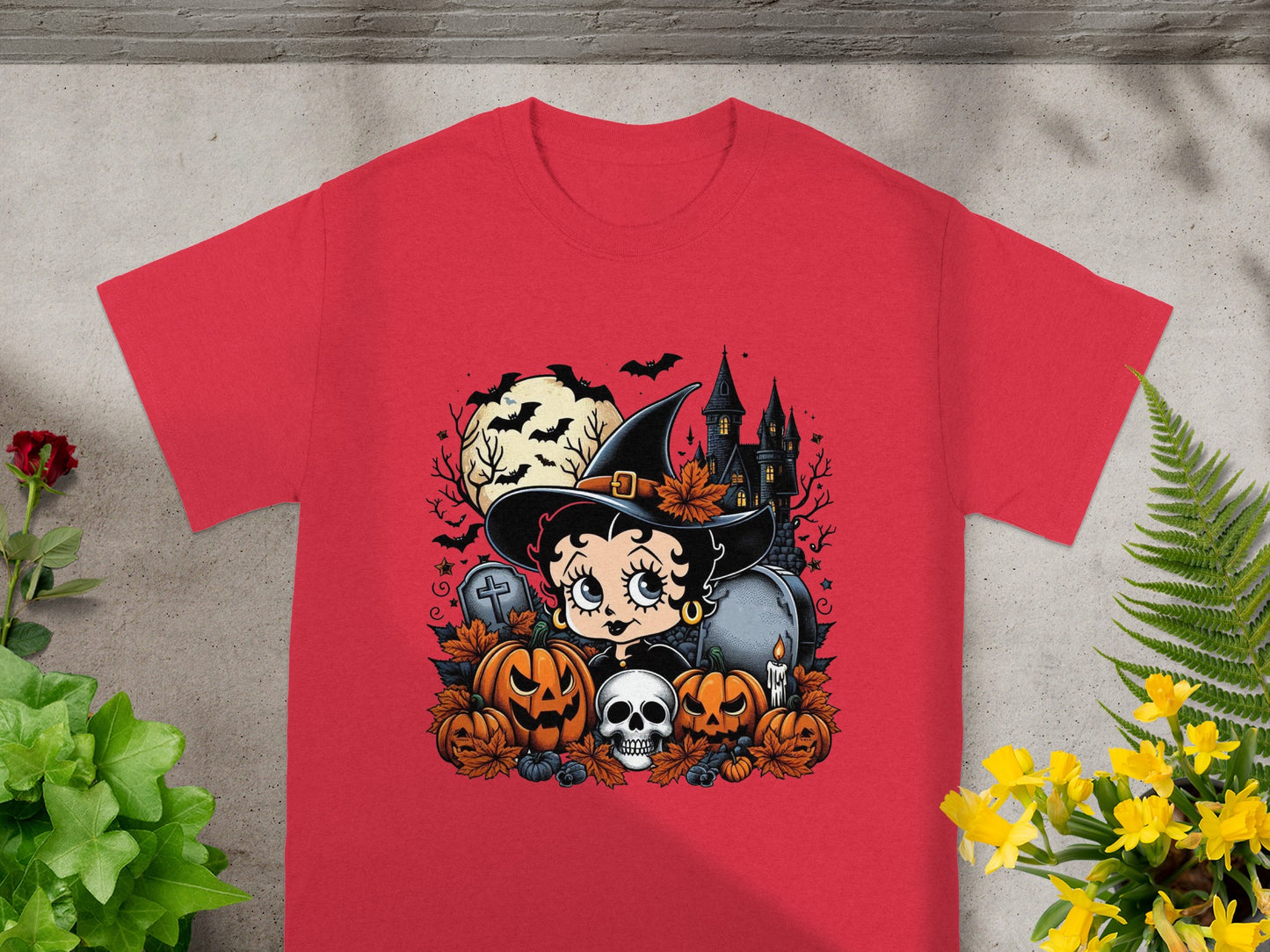 Red t-shirt featuring Betty Boop as a witch surrounded by Halloween decorations.