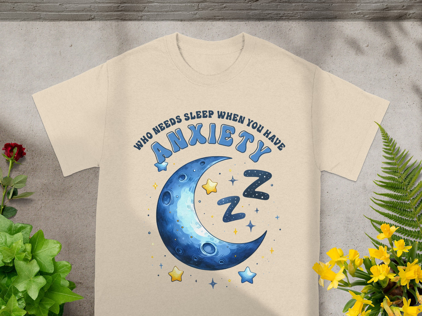 Cream t-shirt with blue text "WHO NEEDS SLEEP WHEN YOU HAVE ANXIETY" and a crescent moon with stars.