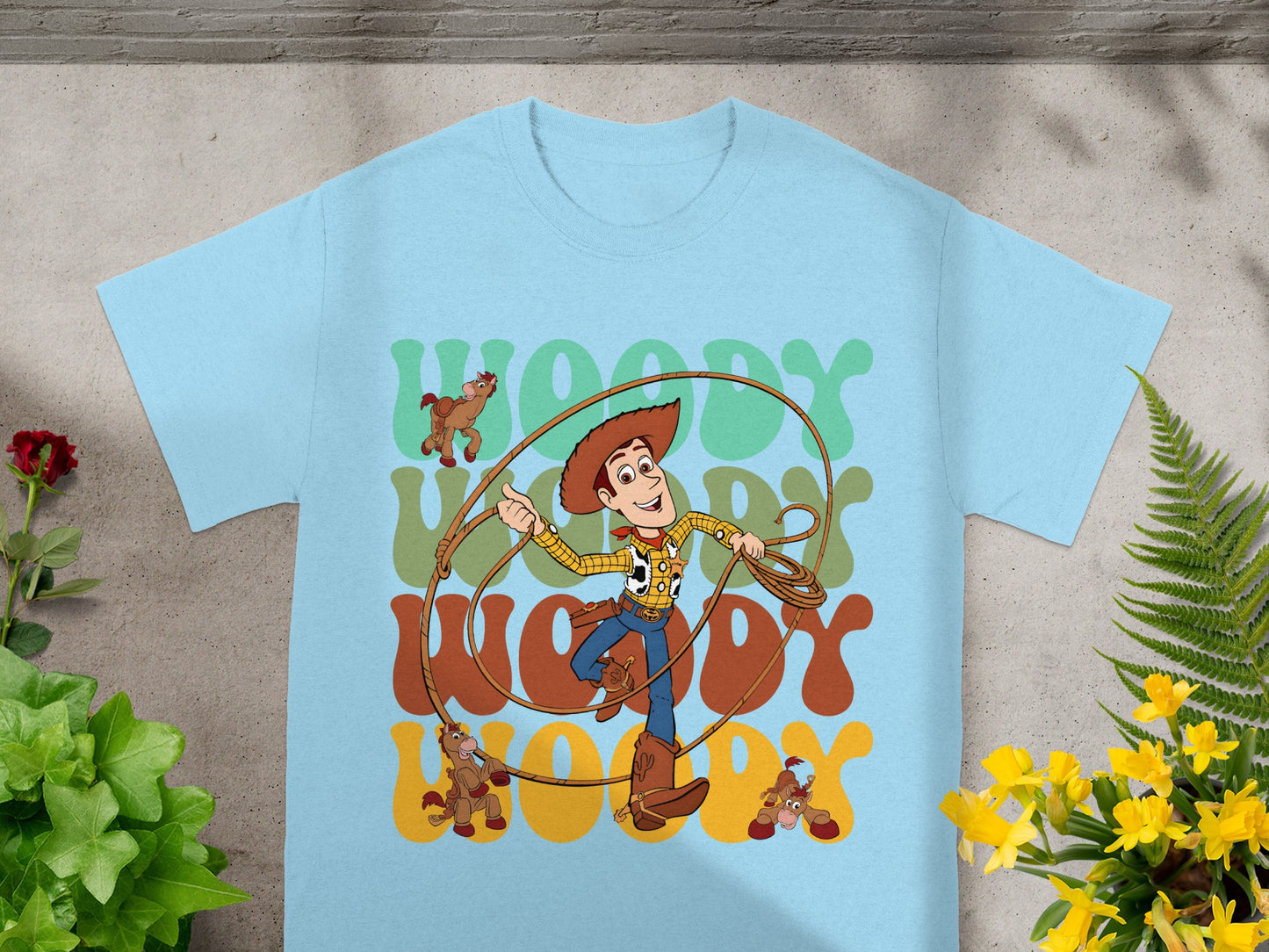 Toy Story's Woody with rope and horses on a light blue t-shirt.