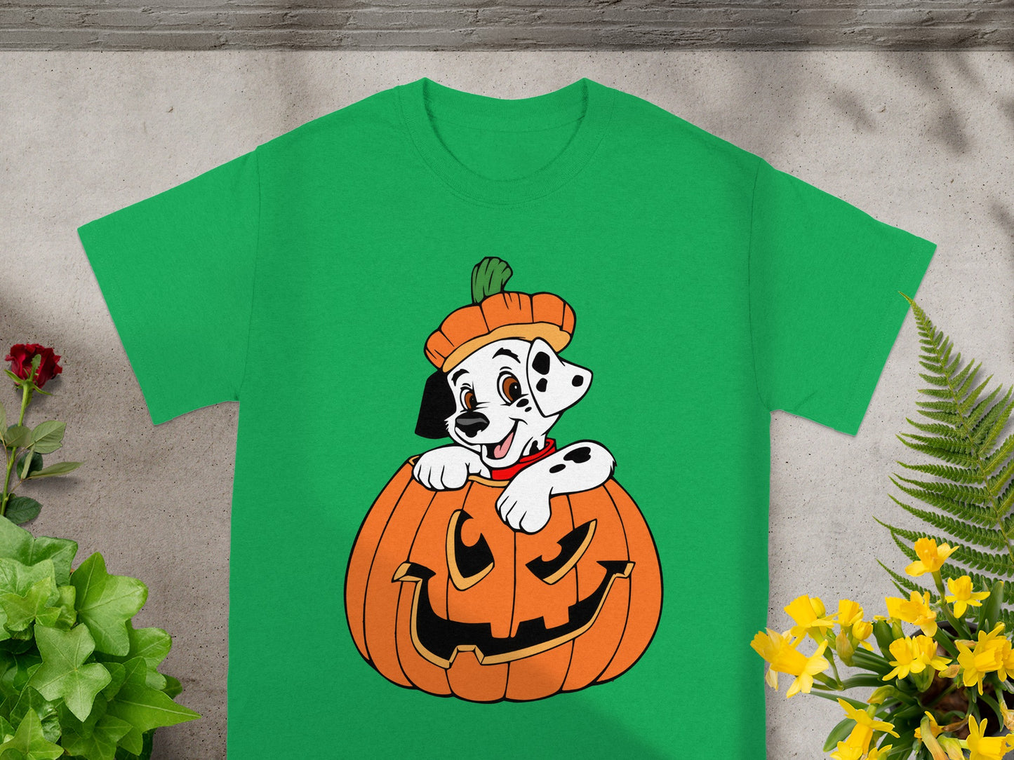 Dalmatian puppy in a pumpkin with a pumpkin hat on a green t-shirt.