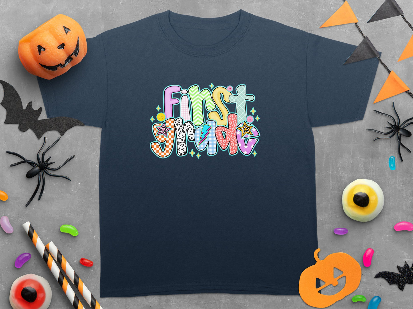 Navy t-shirt with colorful "First Grade" text and Halloween decorations.