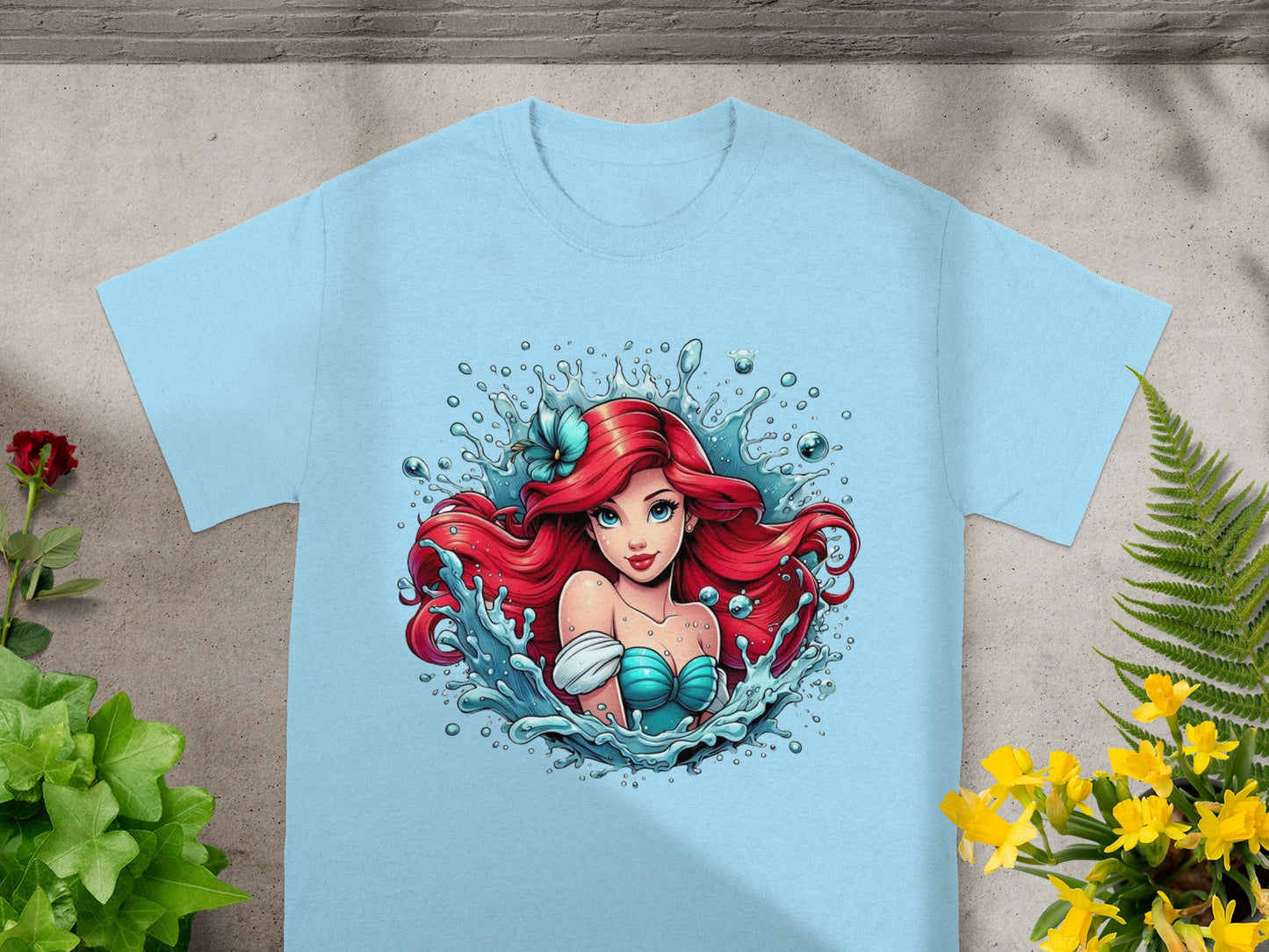 Ariel from The Little Mermaid in blue top surrounded by water splashes.