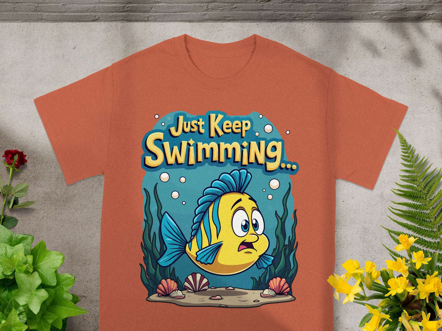 Orange t-shirt with "Just Keep Swimming" and a cartoon fish underwater.