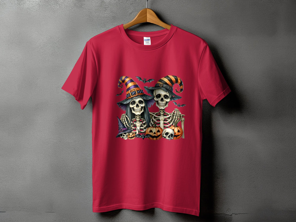 Two skeletons in witch hats with bats and pumpkins on a red t-shirt.