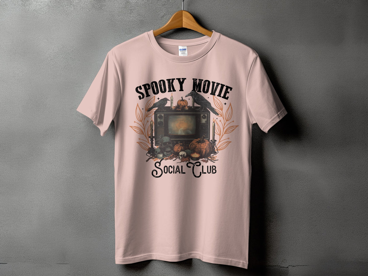 Pink t-shirt with "Spooky Movie Social Club" graphic featuring a vintage TV, crows, pumpkins, and skulls.