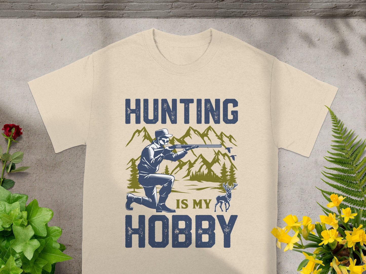 Shirt with "Hunting is my hobby" text, hunter aiming rifle, mountains and deer graphic.