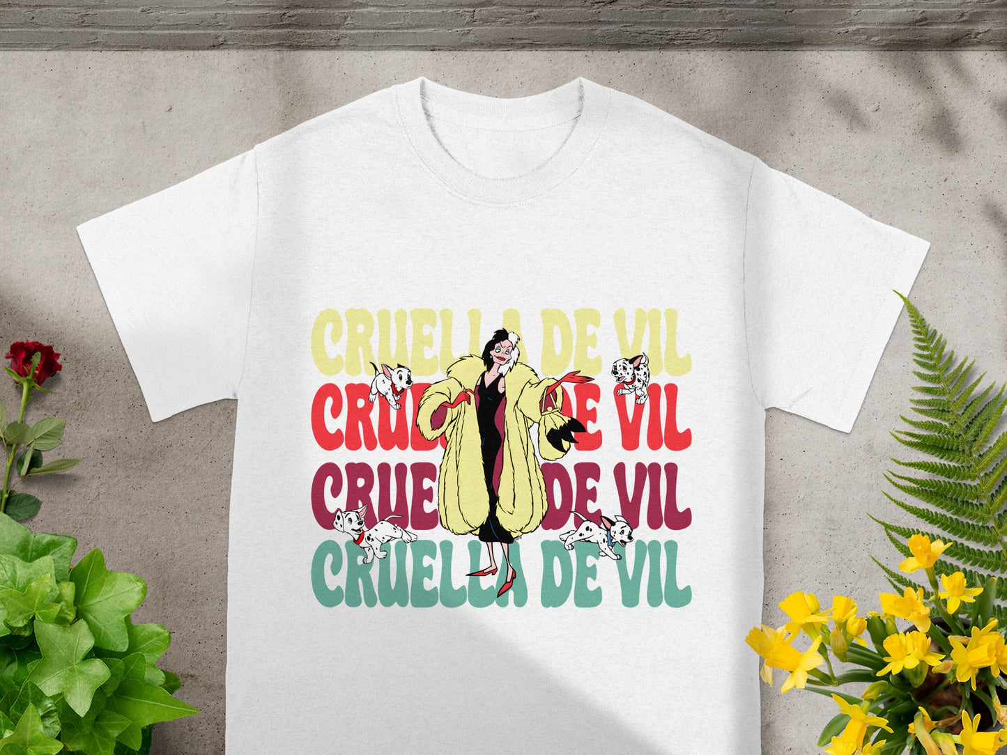 White t-shirt with "Cruella De Vil" text in colorful block letters.