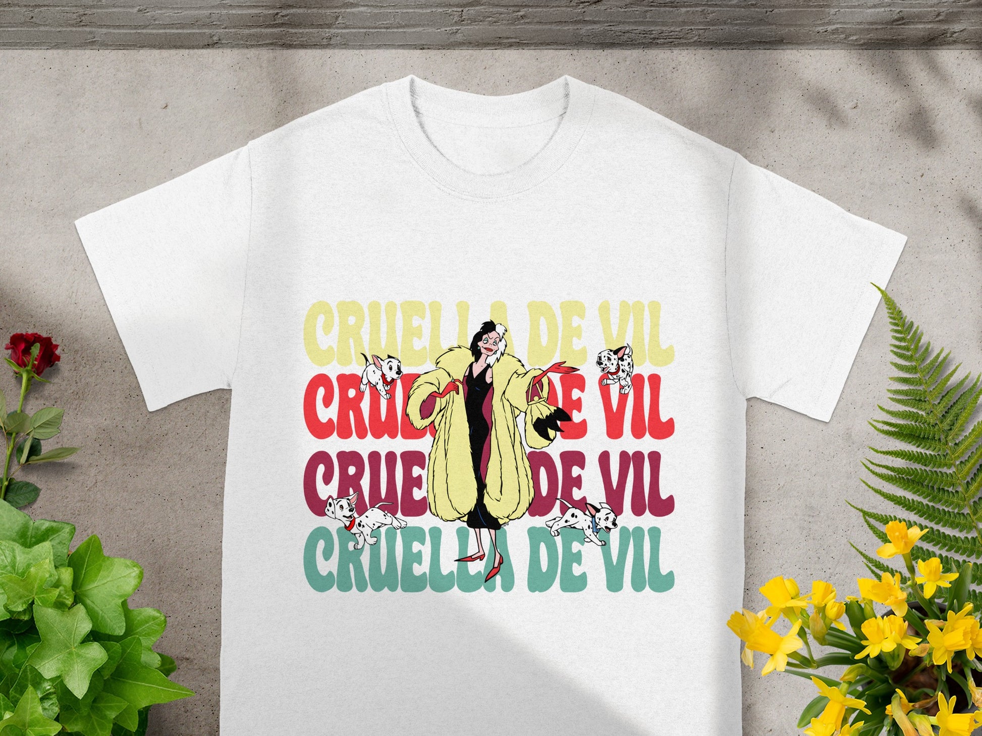 White t-shirt with "Cruella De Vil" text in colorful block letters.
