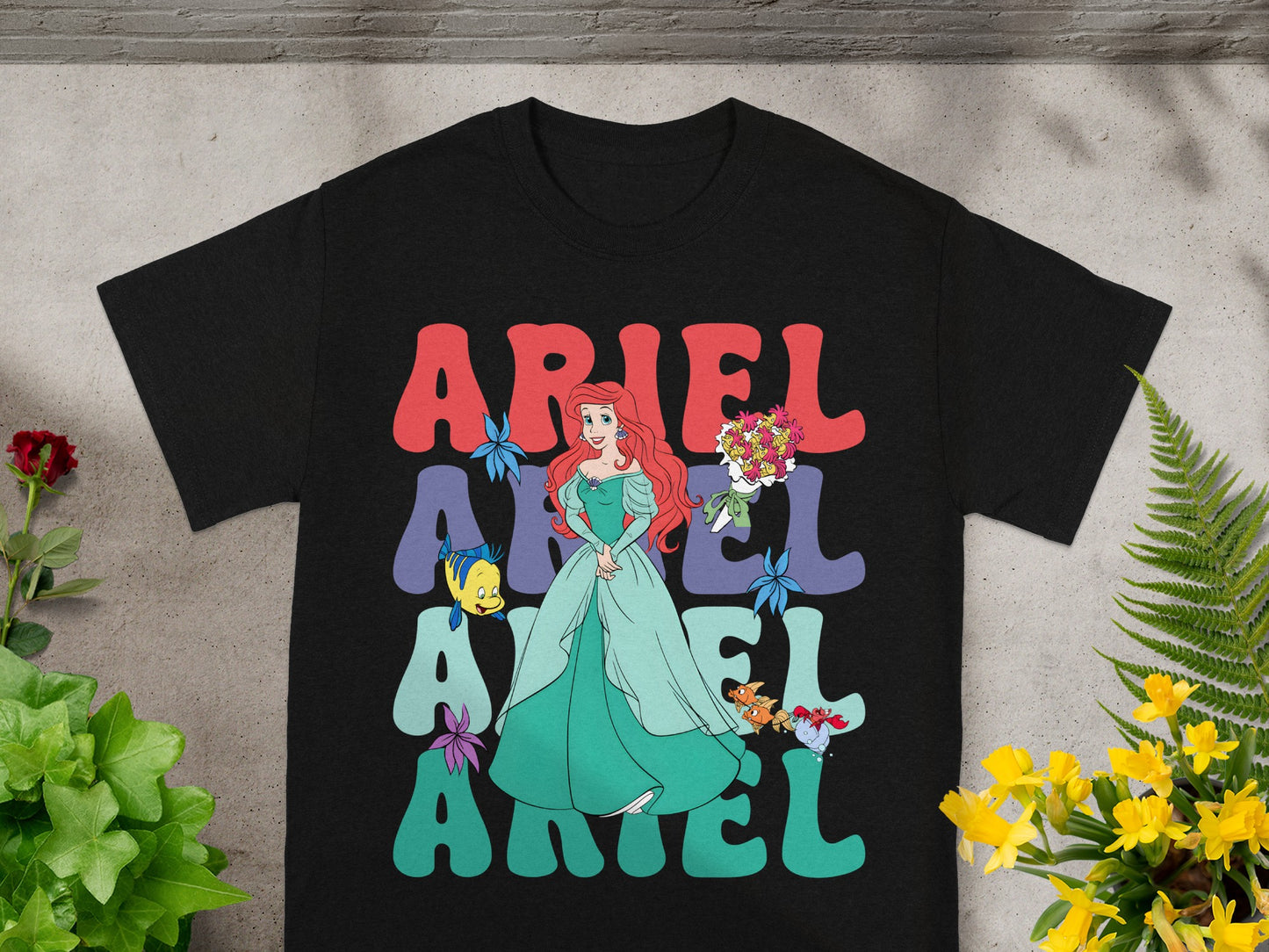 Black t-shirt with Ariel from The Little Mermaid in a green dress and text.