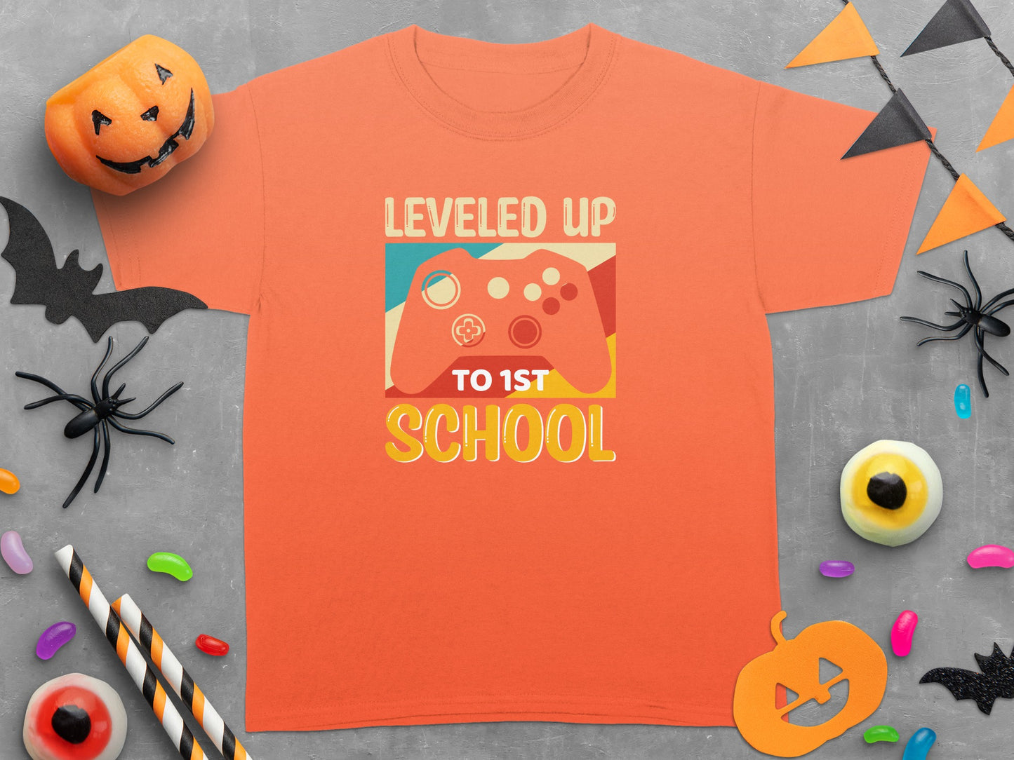 Orange t-shirt with "Leveled Up To 1st School" text and video game controller graphic.