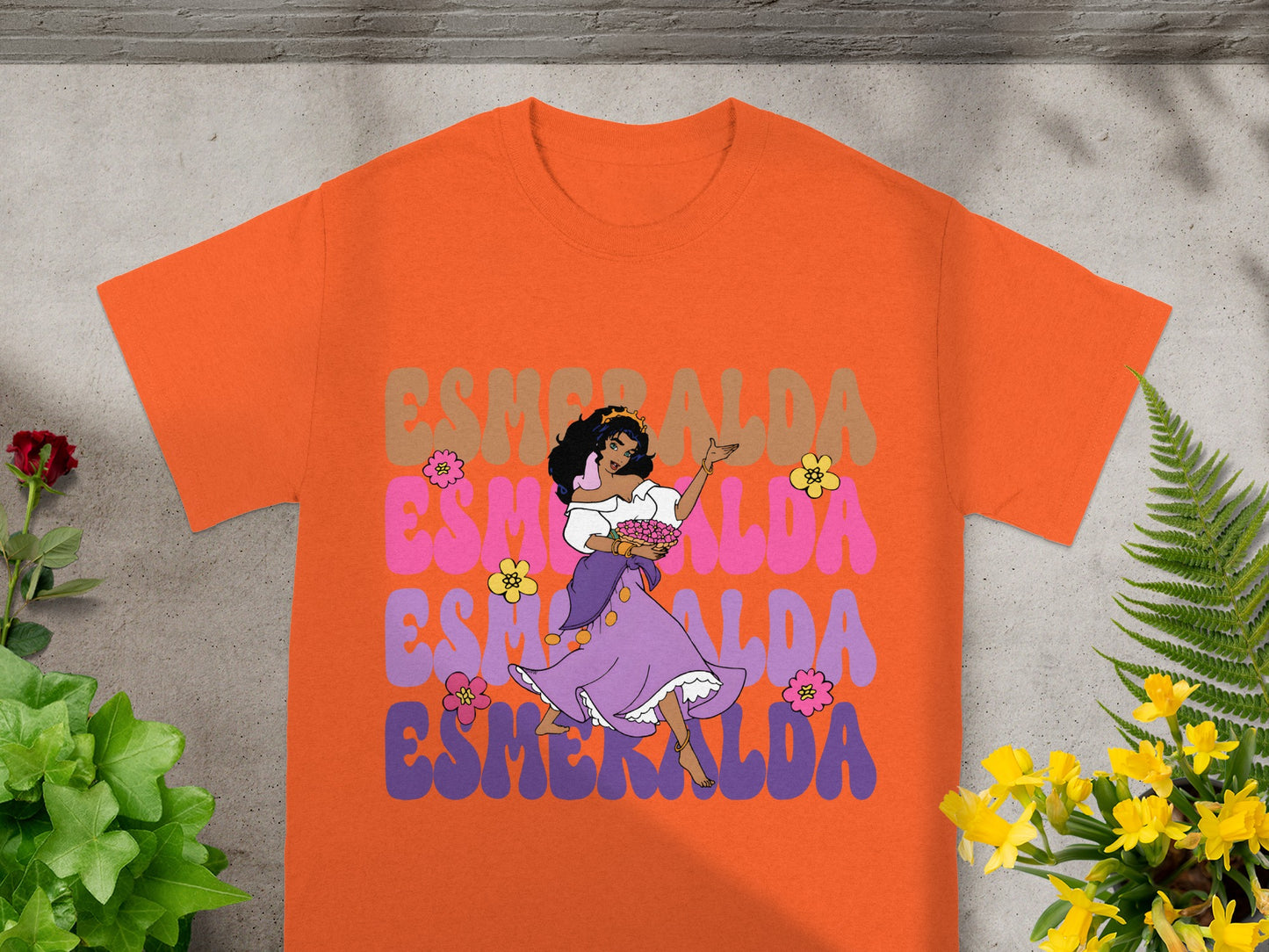 Orange t-shirt with "ESMERALDA" text and a cartoon of a woman holding flowers.