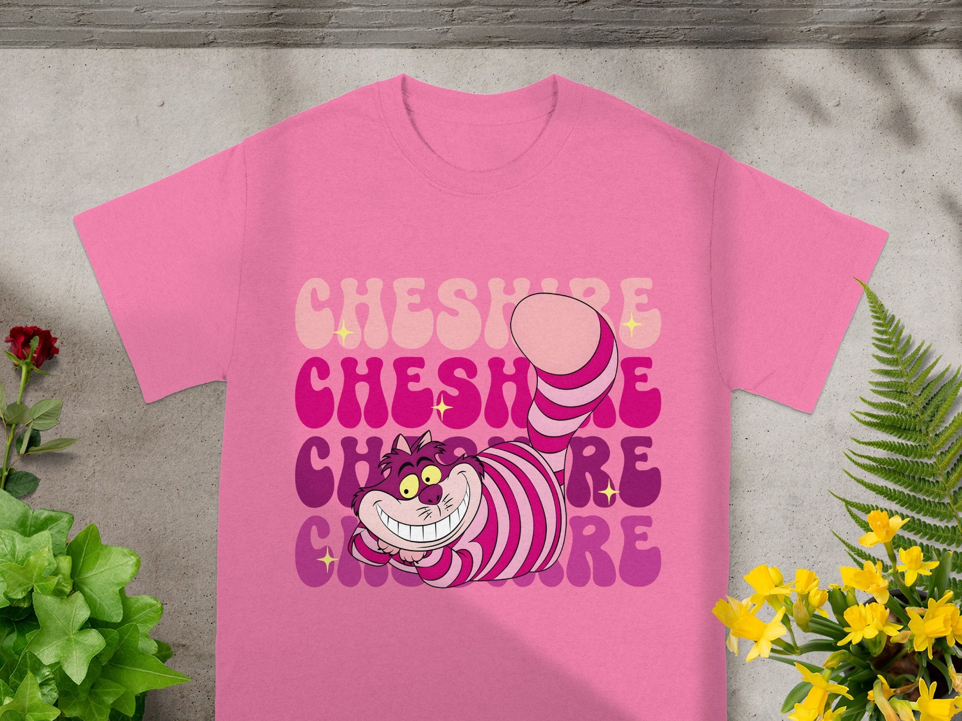 Pink t-shirt with a striped Cheshire Cat design and text.