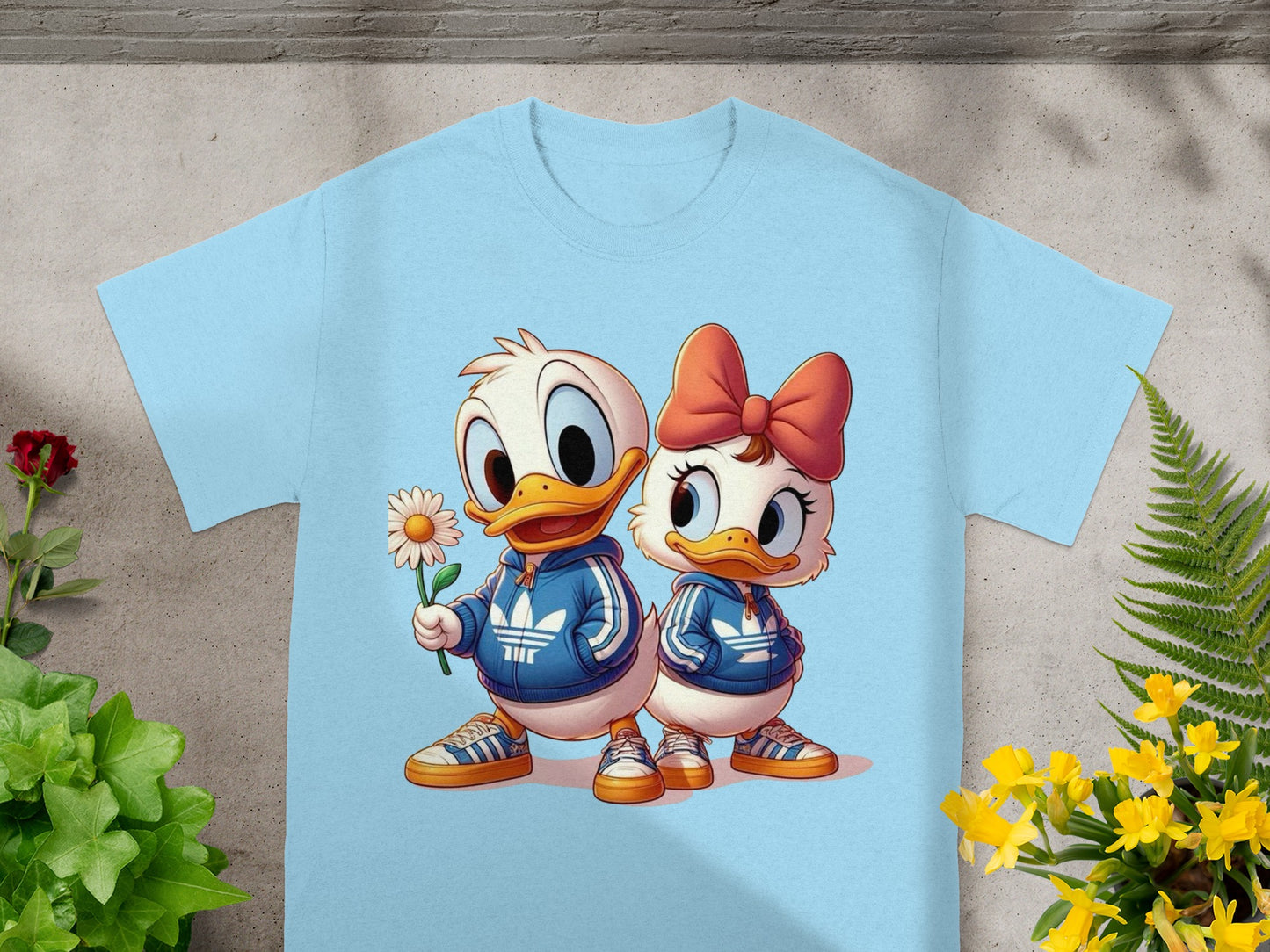 Light blue t-shirt with cartoon ducks in tracksuits holding a daisy.