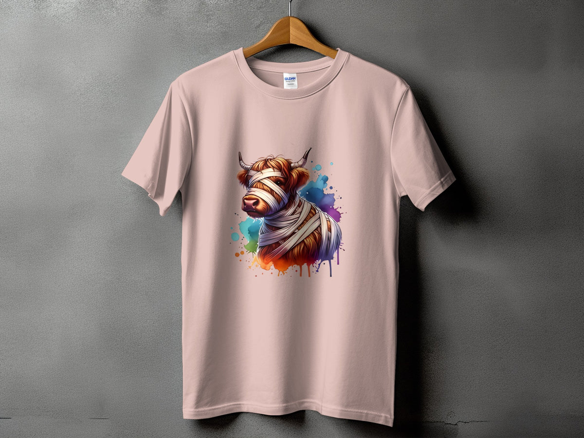 Pink t-shirt with a watercolor highland cow wrapped in bandages graphic.