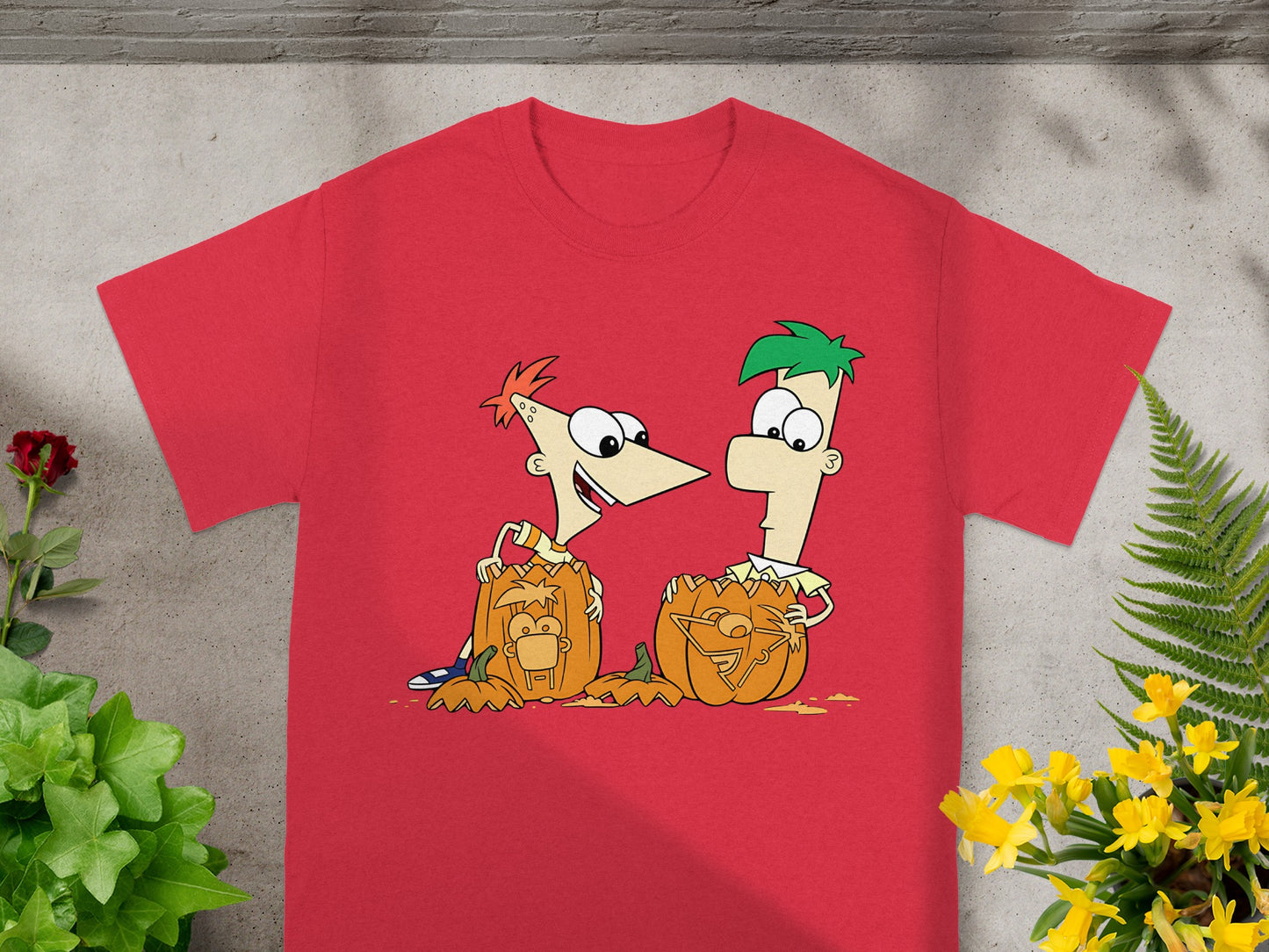 Phineas and Ferb carve pumpkins with their faces on them on a red t-shirt.