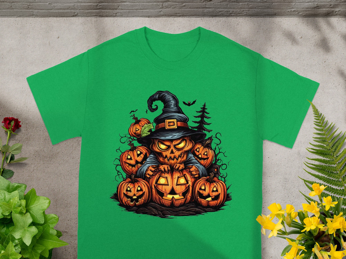 Jack-o'-lantern scarecrow with witch hat and pumpkins on green t-shirt.