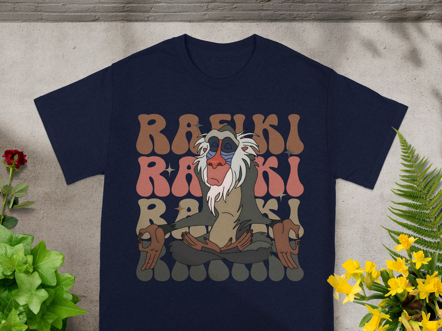 Rafiki meditating with colorful text on a navy t-shirt.