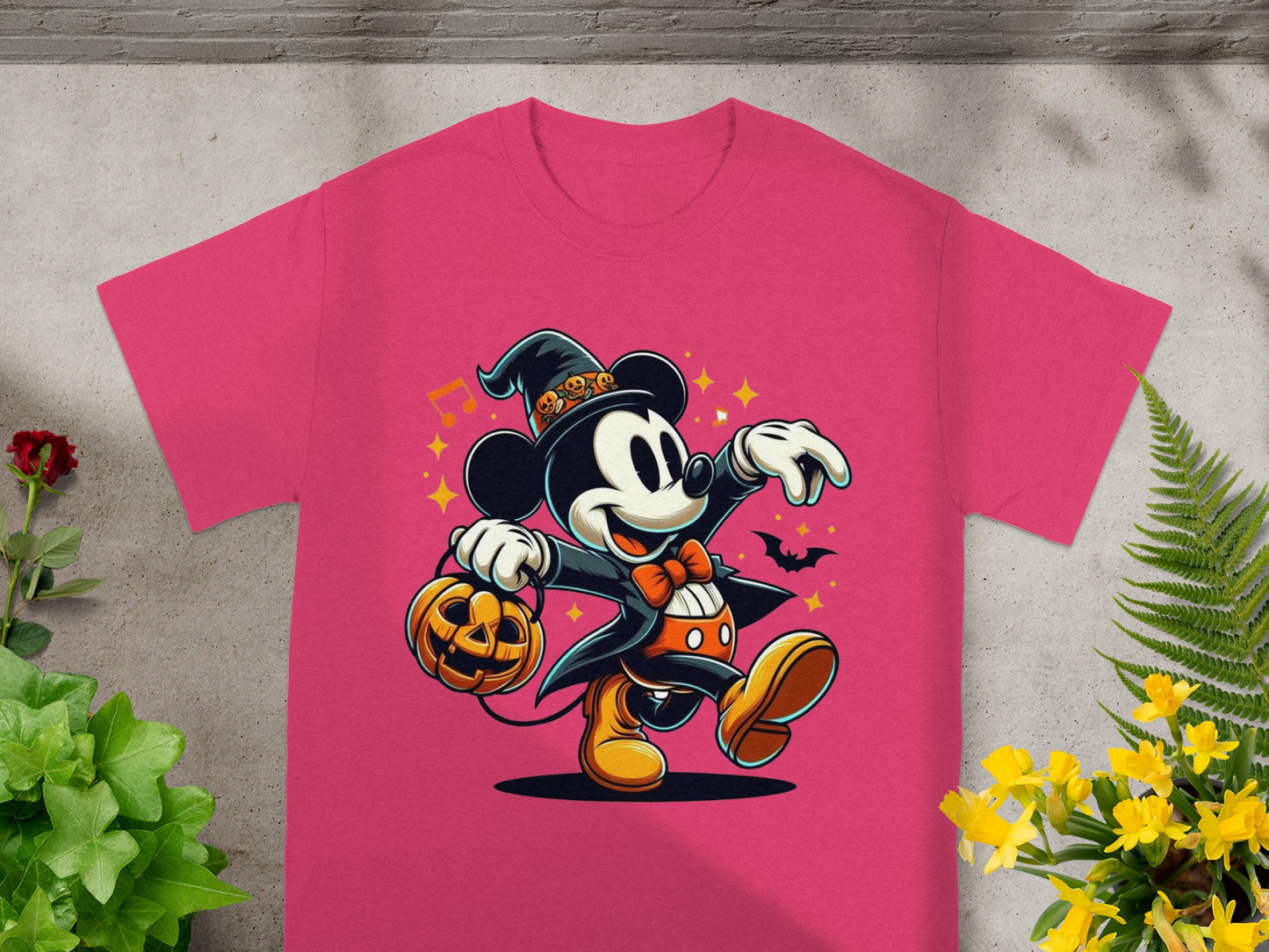 Mickey Mouse in a witch hat holding a pumpkin on a pink t-shirt.