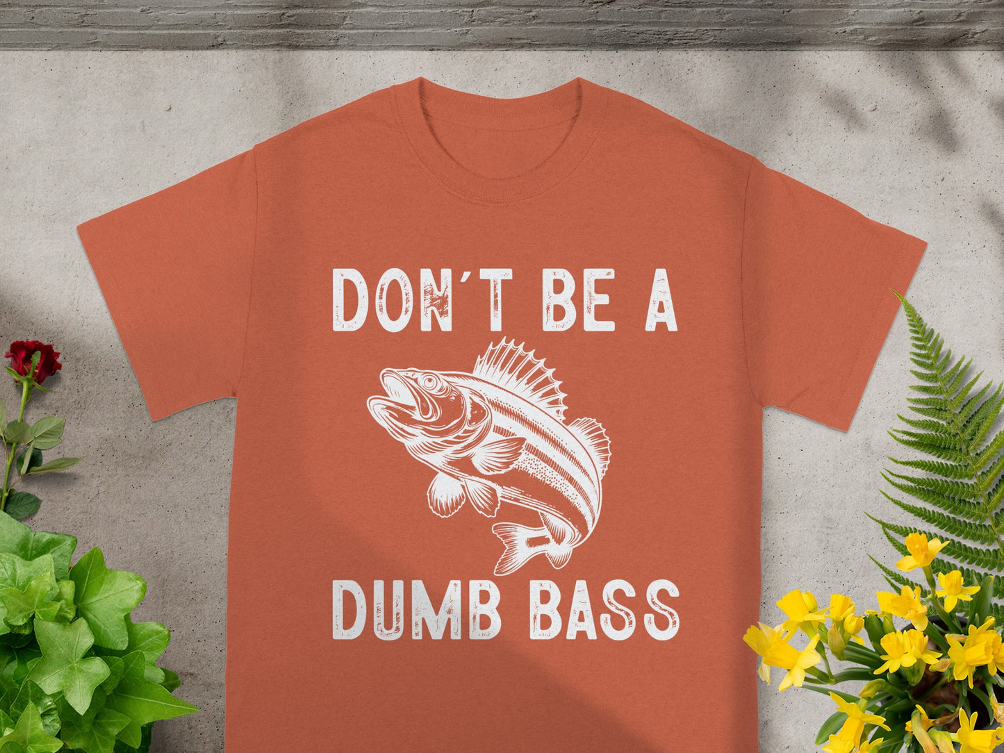 Orange t-shirt with white text "DON'T BE A DUMB BASS" and bass fish graphic.