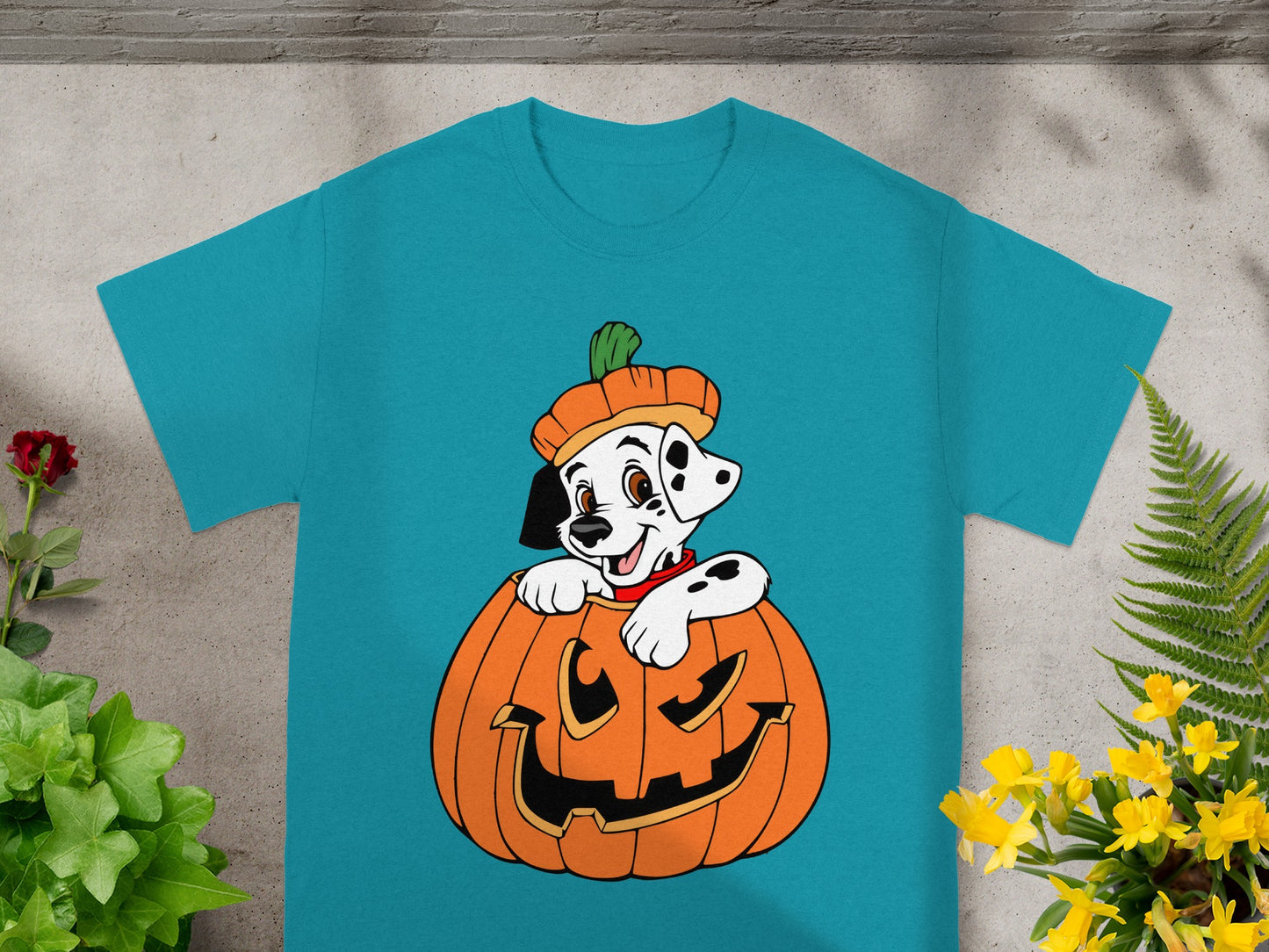 Dalmatian puppy wearing a pumpkin hat in a jack-o'-lantern on a teal t-shirt.