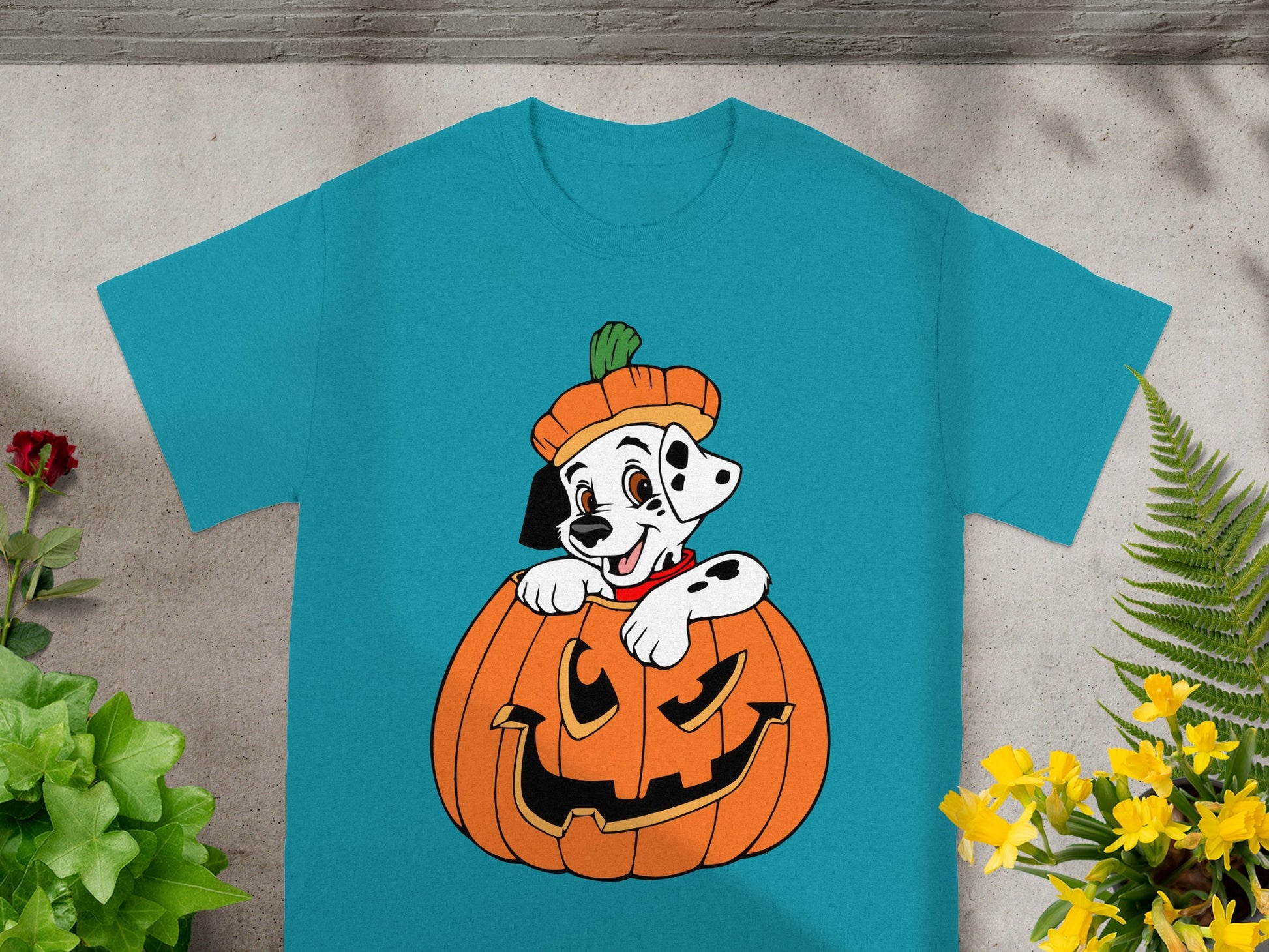 Dalmatian puppy wearing a pumpkin hat in a jack-o'-lantern on a teal t-shirt.