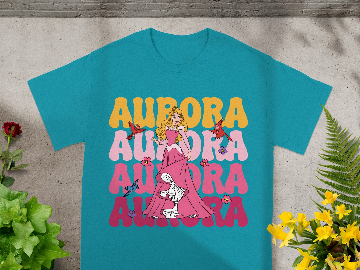 Aurora and Sleeping Beauty graphic on a teal t-shirt.