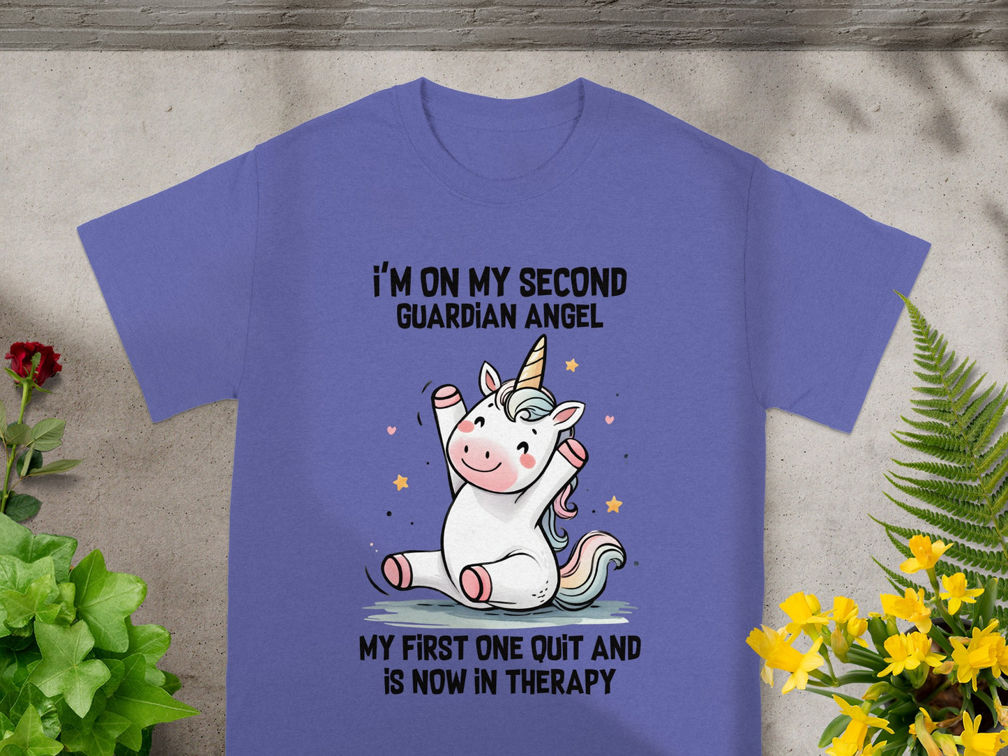 Purple t-shirt with a cartoon unicorn and text: "I'm on my second guardian angel. My first one quit and is now in therapy."