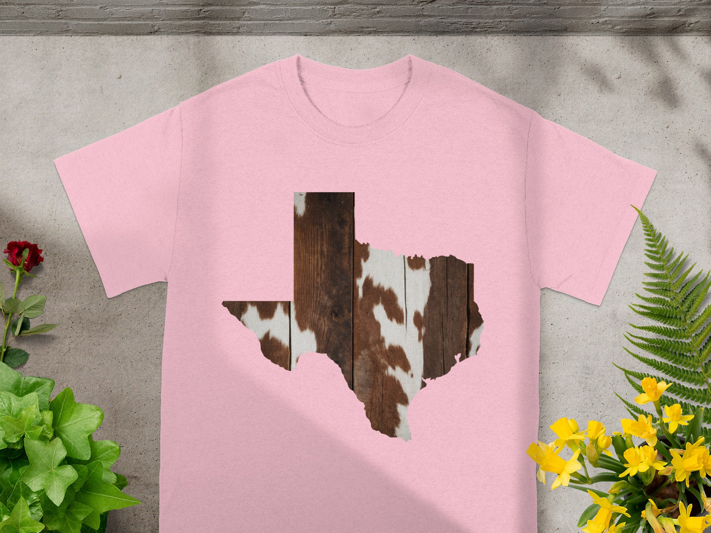 Pink t-shirt with Texas shape graphic in wood and cowhide pattern.