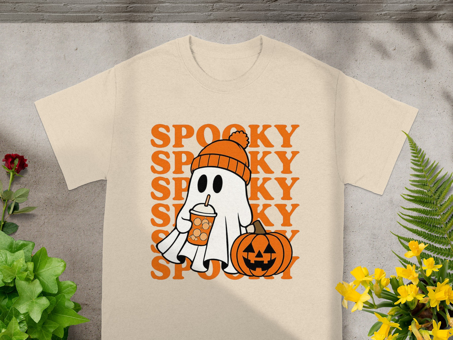 Cream t-shirt with a cartoon ghost holding a drink and a pumpkin, and text "SPOOKY".