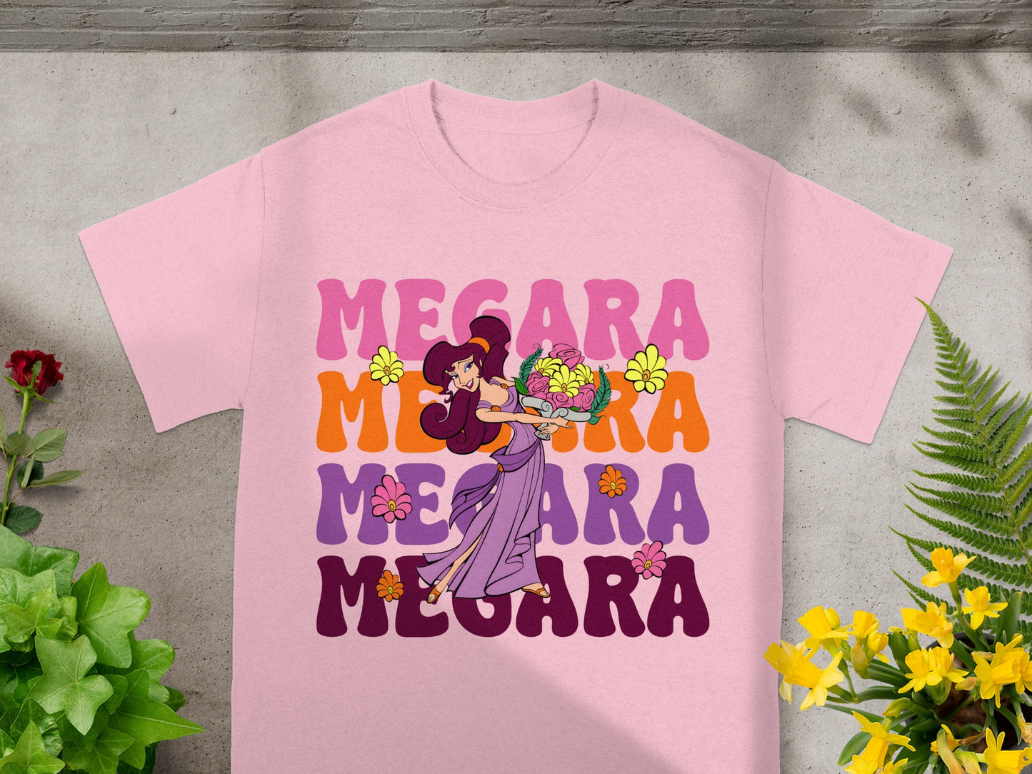 Pink t-shirt with "Megara" repeated in colorful text and a floral illustration.