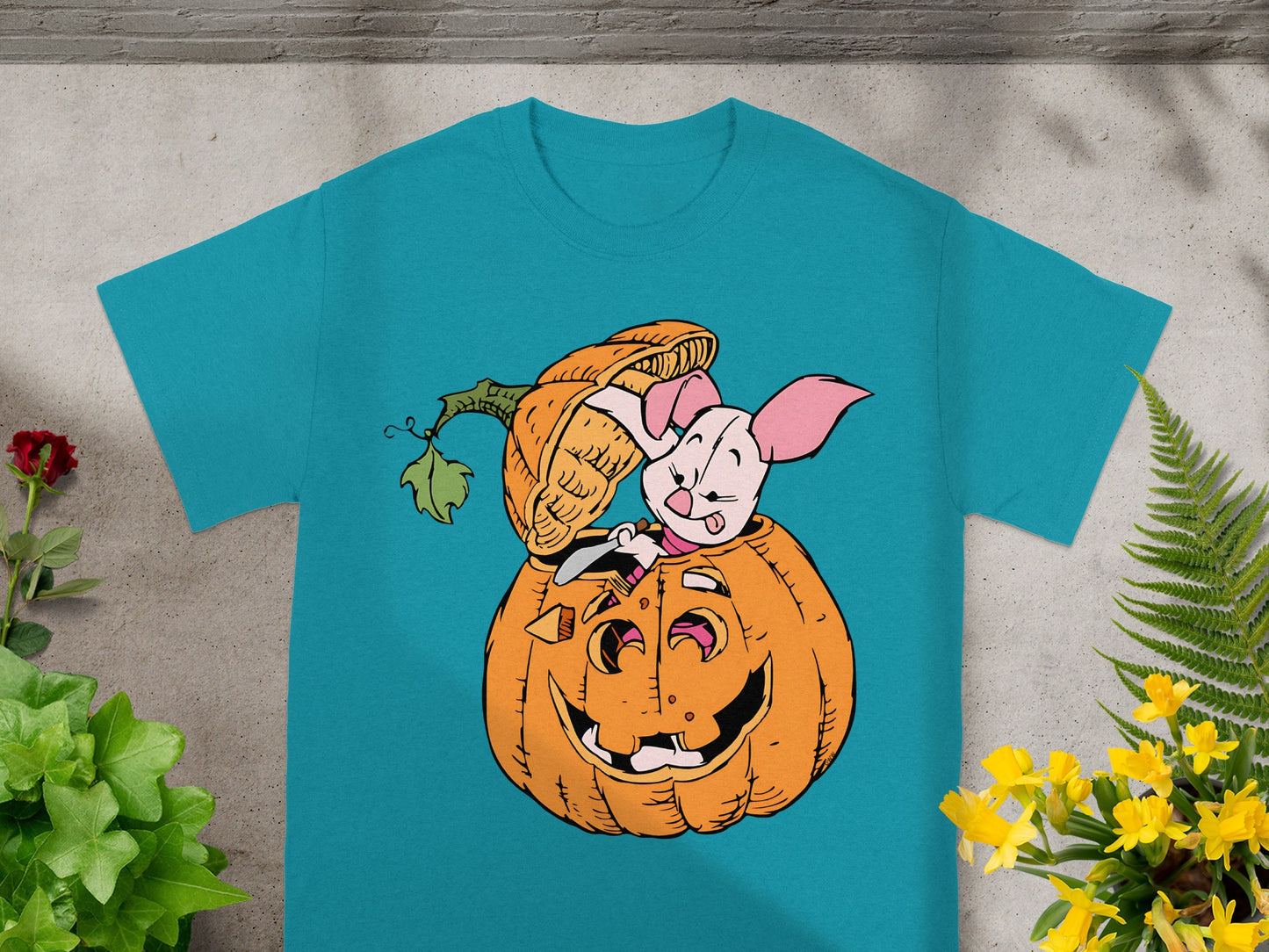 Piglet peeking out of a carved Halloween pumpkin on a teal t-shirt.