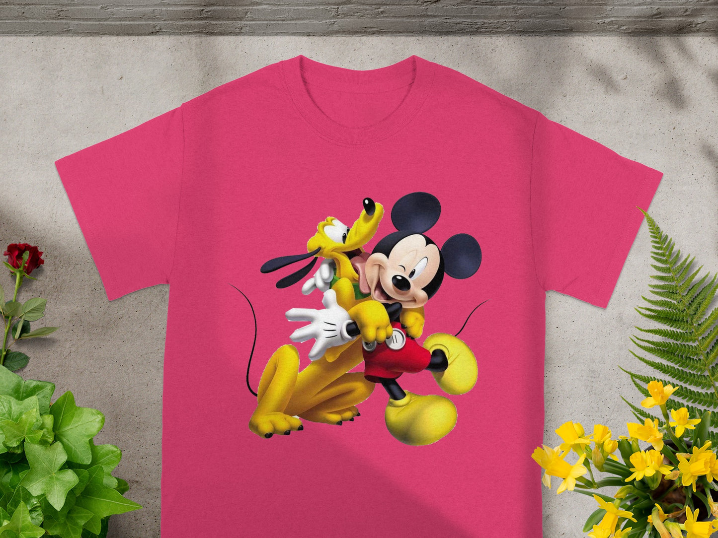 Pink t-shirt featuring Mickey Mouse and Pluto embracing, against a white background.