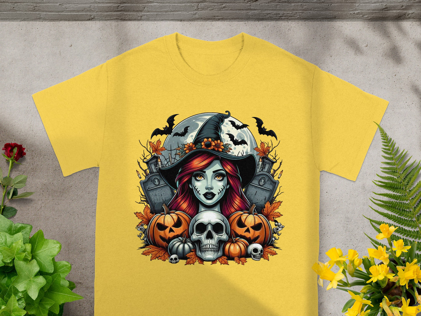 Halloween witch and skull graphic on a yellow t-shirt with pumpkins and gravestones.