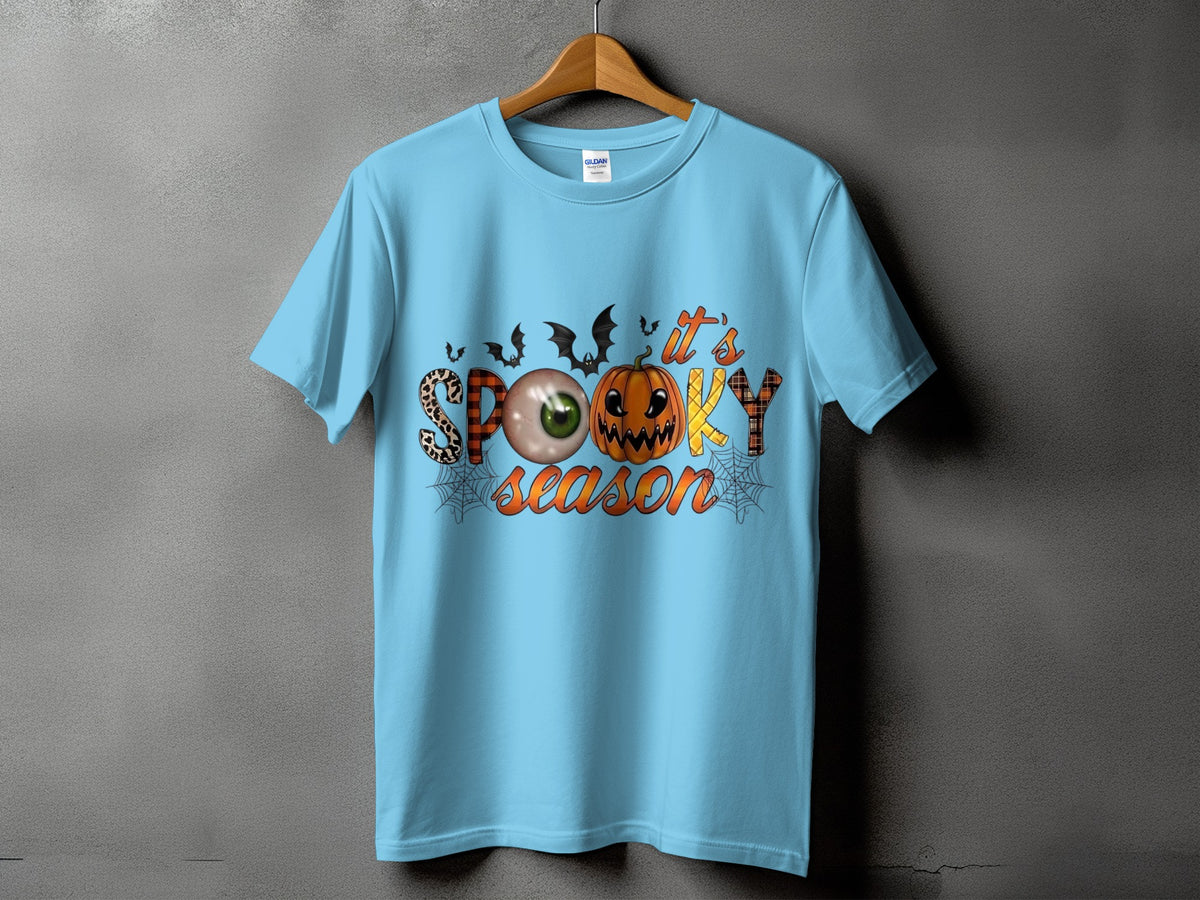 Light blue t-shirt with "It's Spooky Season" Halloween graphic featuring pumpkin and eyeball.