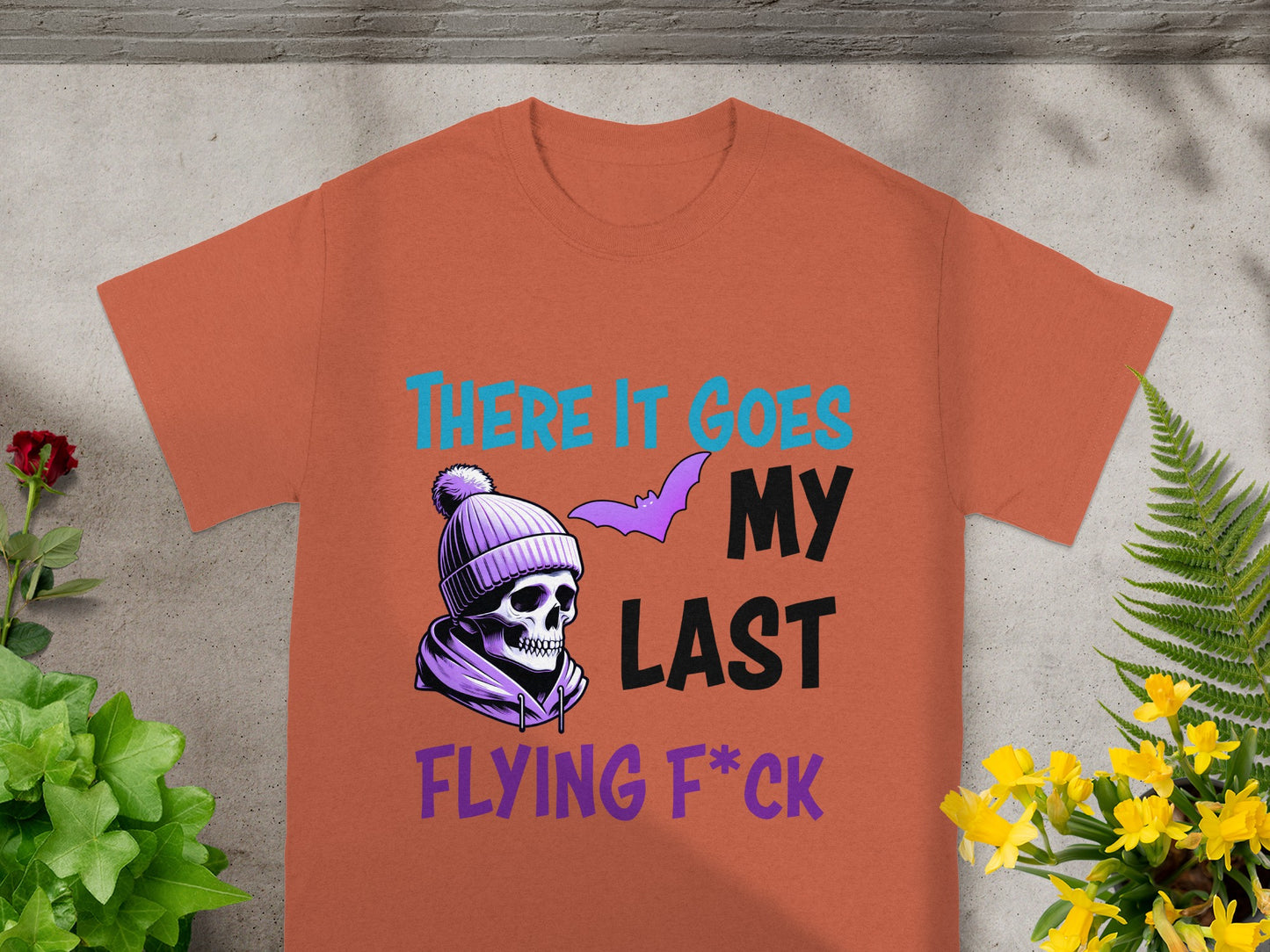 Orange t-shirt with a skull wearing a beanie and the text "THERE IT GOES MY LAST FLYING F*CK".