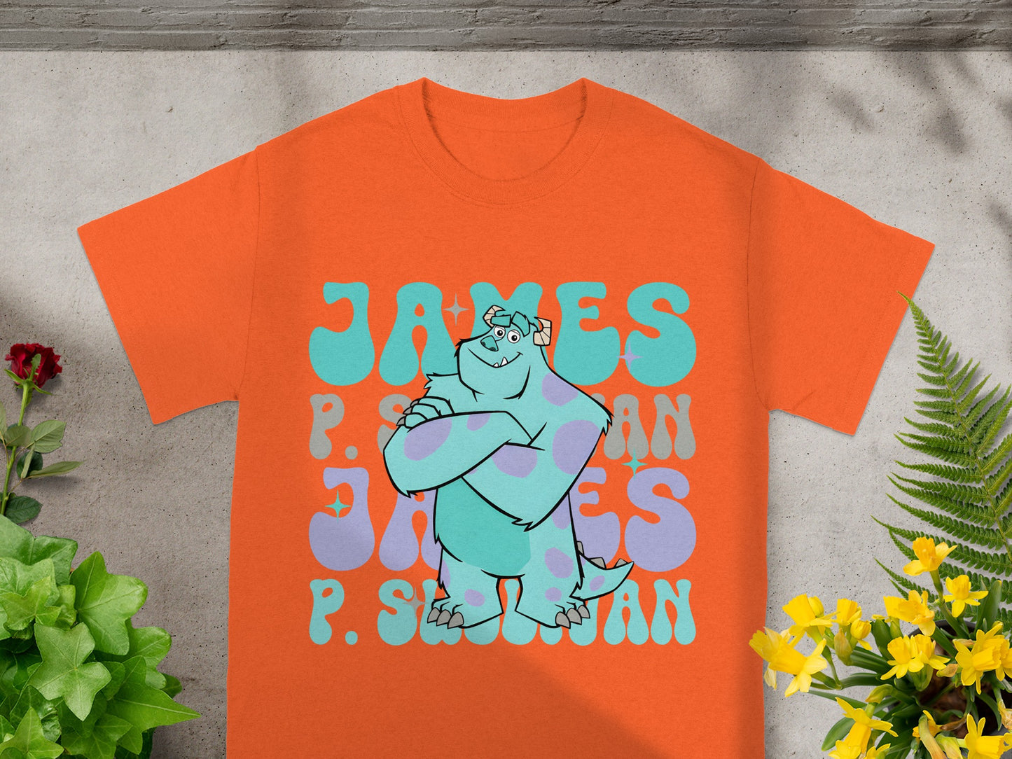 Orange t-shirt with cartoon character James P. Sullivan and psychedelic text.