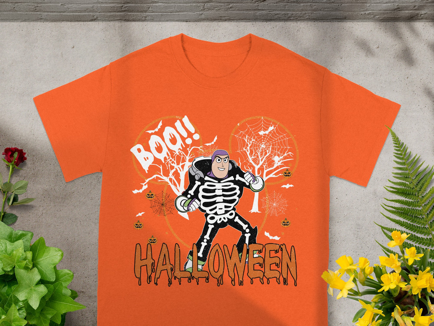 Buzz Lightyear in skeleton costume on orange Halloween shirt with pumpkins and webs.