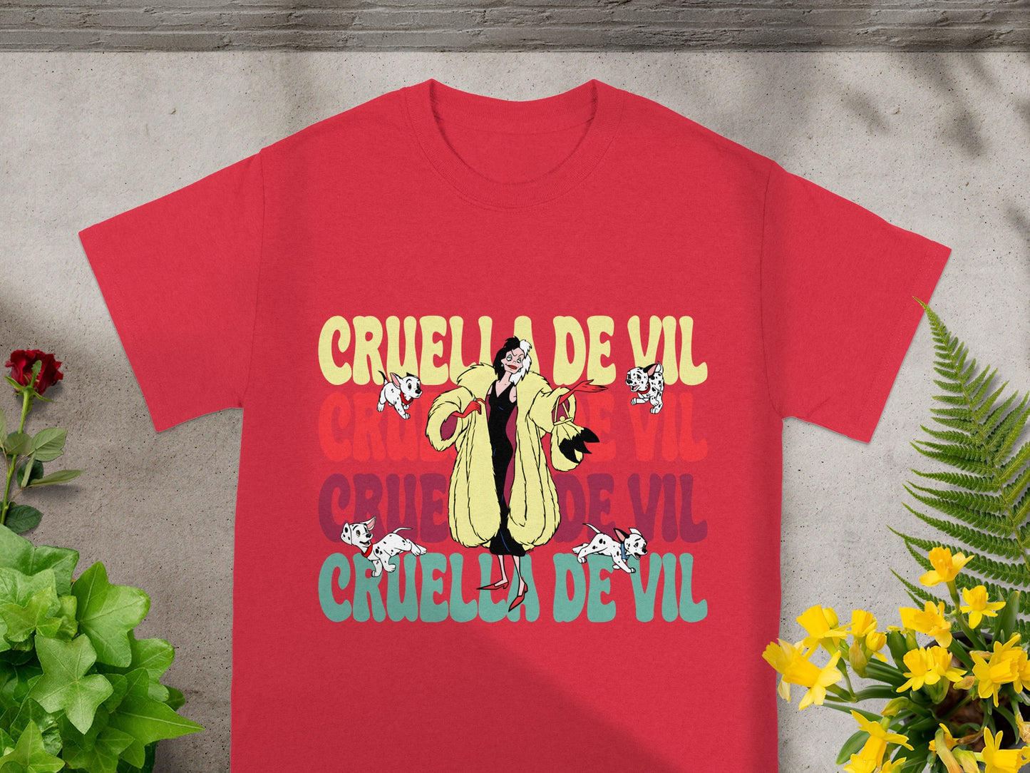 Red t-shirt with "Cruella de Vil" repeated in colorful distressed text.