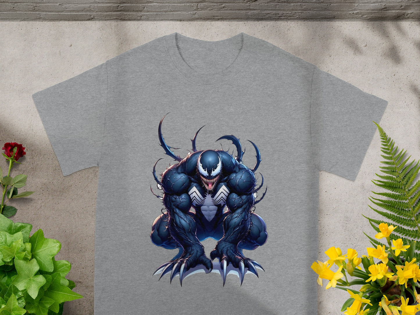 Venom character illustration on a grey t-shirt, partially obscured by plants.