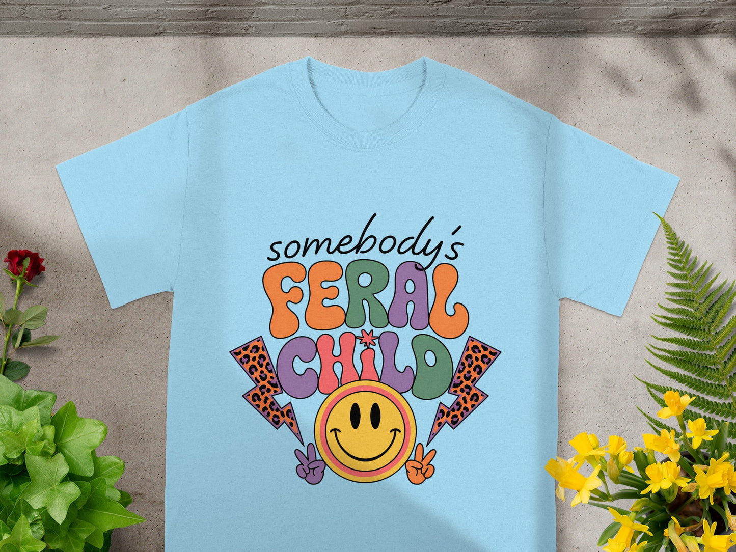 Light blue t-shirt with the text "somebody's FERAL CHILD" and smiley face.