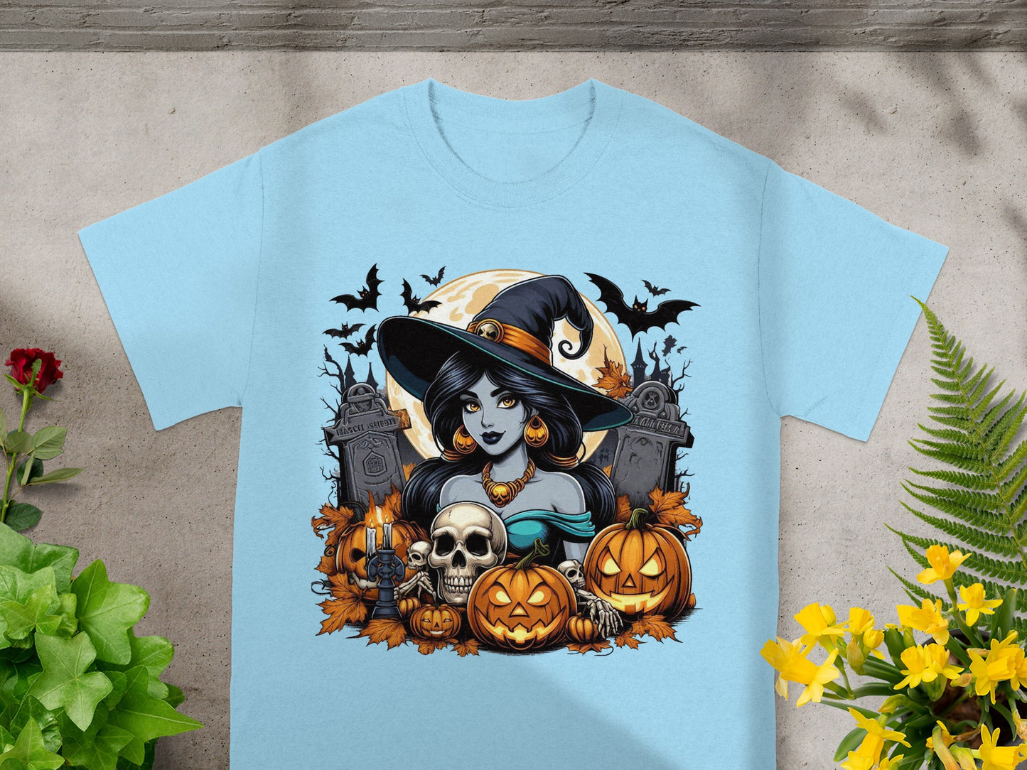 Halloween t-shirt graphic featuring a witch, pumpkins, skulls, bats, and gravestones.