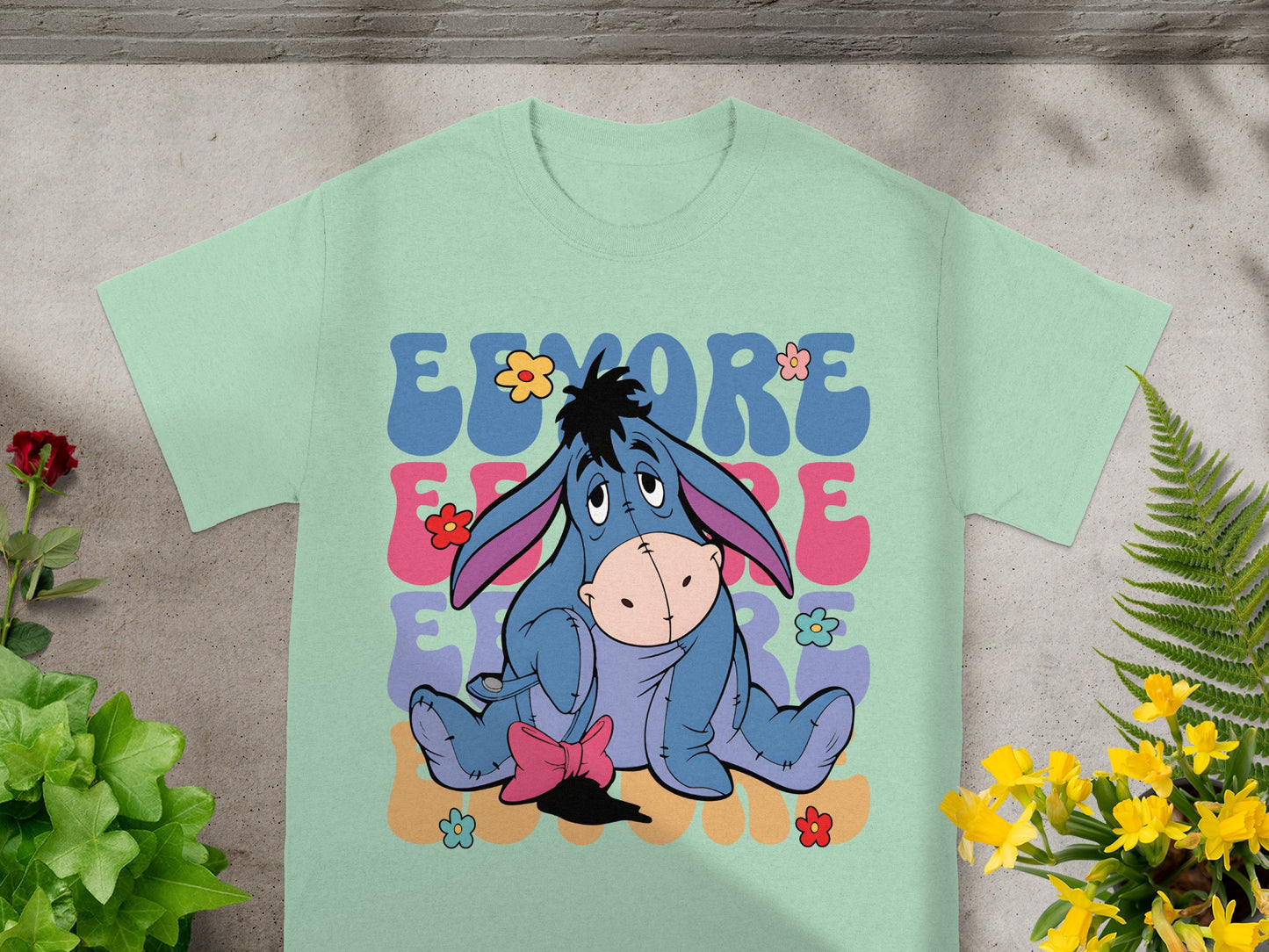 Eeyore sitting with colorful flowers and "EEYORE" text.