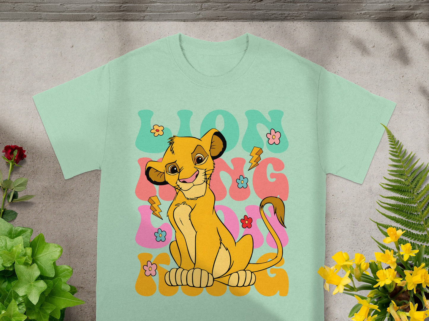 Mint t-shirt with Simba from The Lion King smiling and floral graphics.