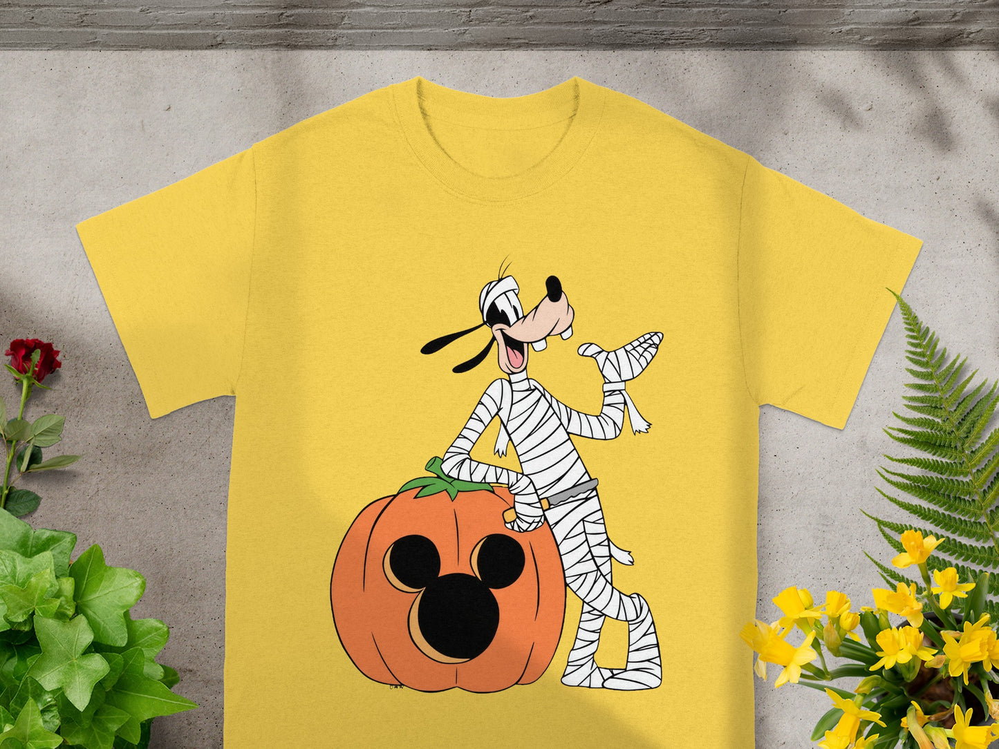 Goofy dressed as a mummy leaning on a Mickey Mouse pumpkin.