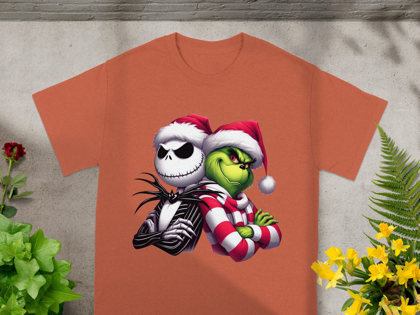Jack Skellington and the Grinch wear Santa hats on an orange t-shirt.
