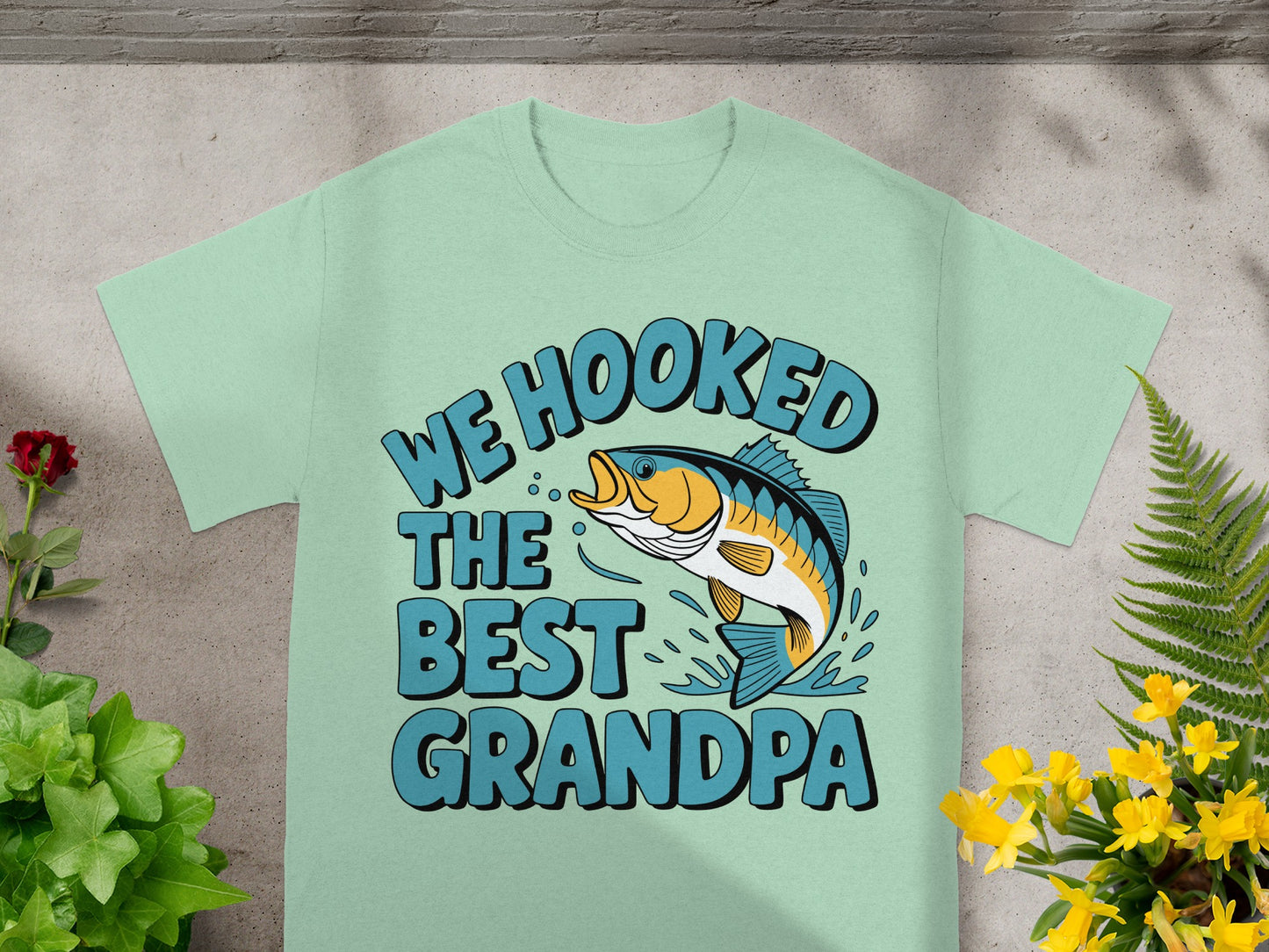 T-shirt with graphic of a leaping fish and text "WE HOOKED THE BEST GRANDPA".
